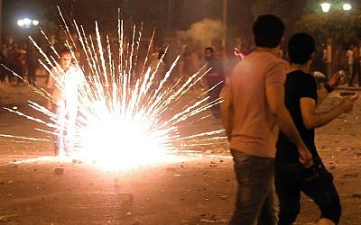 A protester watches fireworks burn during clashes in Cairo that left one dead, on Saturday. (photo credit: AP/Ahmed Ali)
