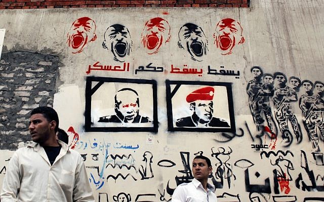 Egyptian men pass by a wall graffiti depicting two members of the ruling Supreme Council of the Armed Forces, with Arabic that reads "Down with the military rule," in downtown Cairo, Wednesday (photo credit: AP/Nasser Nasser) Egyptian men pass by a wall graffiti depicting two members of the ruling Supreme Council of the Armed Forces, with Arabic that reads "Down with the military rule," in downtown Cairo, Wednesday (photo credit: AP/Nasser Nasser)