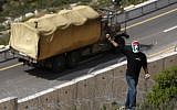Illustrative: A masked Palestinian demonstrator holds stones during a protest against Israel's separation barrier in the West Bank village of Bil'in, near Ramallah, Friday. (photo credit: AP/Majdi Mohammed)