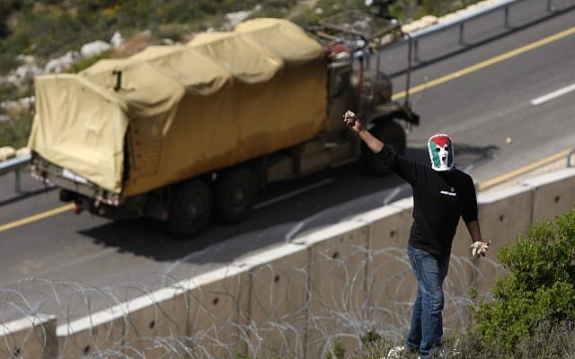 Illustrative: A masked Palestinian demonstrator holds stones during a protest against Israel's separation barrier in the West Bank village of Bil'in, near Ramallah, Friday. (photo credit: AP/Majdi Mohammed) Illustrative: A masked Palestinian demonstrator holds stones during a protest against Israel's separation barrier in the West Bank village of Bil'in, near Ramallah, Friday. (photo credit: AP/Majdi Mohammed)