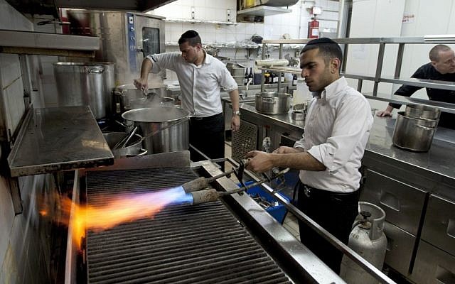 Chef Noam Dekkers , in the back, watches workers of the Tel Aviv-Jaffa rabbinate blow-torch the grill stove in one of the kitchens in Liliyot restaurant making it kosher for the Jewish holiday of Passover. (photo credit: AP)