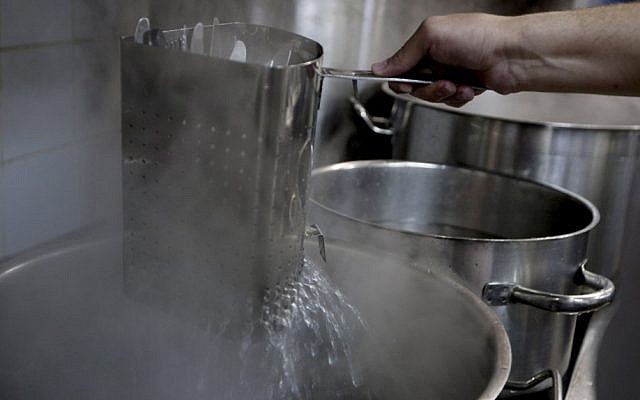 A worker of the Tel Aviv-Jaffa rabbinate immerses dishes from boiling water to remove remains of leavened food in one of the kitchens in Liliyot. (photo credit: AP) A worker of the Tel Aviv-Jaffa rabbinate immerses dishes from boiling water to remove remains of leavened food in one of the kitchens in Liliyot. (photo credit: AP)