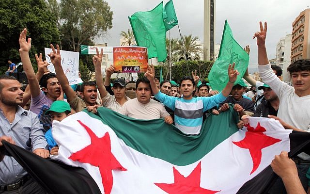 Supporters of an Islamic group and of former Lebanese prime minister Saad Hariri's Future Movement wave party flags and a giant Syrian revolution flag during a demonstration against the Syrian regime to show solidarity with the Syrian people after Friday prayers in Beirut, Lebanon (photo credit: Bilal Hussein/AP)