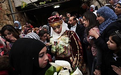 Maha Surougi (center) walks towards Thaer Qasem, the groom, during their wedding in the West Bank village of Deir Istiya, near Nablus. The bride and the groom, Syrian citizens with Palestinian roots, were invited by the Palestinian government to celebrate their marriage in the West Bank. (photo credit: AP/Bernat Armangue)