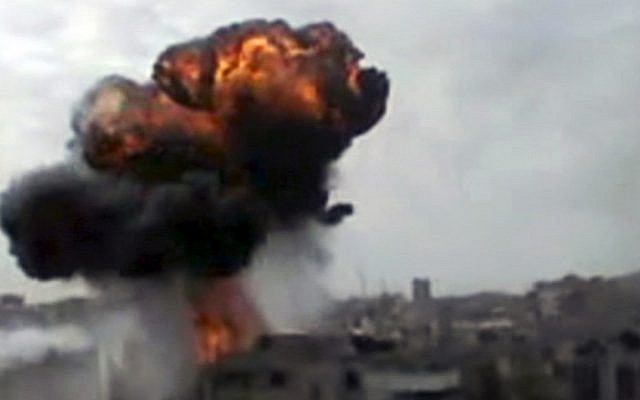 A plume of smoke rises over a neighborhood in Homs Sunday (photo credit: AP/Shaam News Network)
