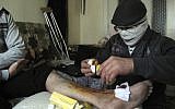 An injured man gets treated in a Damascus neighborhood Tuesday (photo credit: AP)