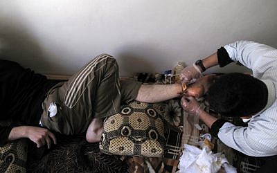 A volunteer doctor treats a wounded protester in a neighborhood of Damascus (photo credit: AP)