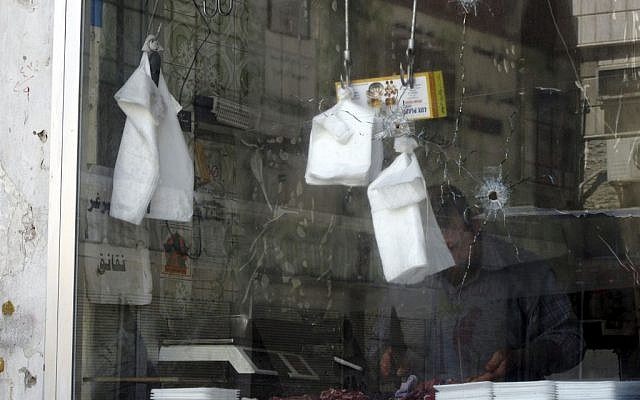 A butcher works in his shop damaged in recent fighting between the government troops and rebels in a Damascus neighborhood, Syria (photo credit: AP Photo) A butcher works in his shop damaged in recent fighting between the government troops and rebels in a Damascus neighborhood, Syria (photo credit: AP Photo)