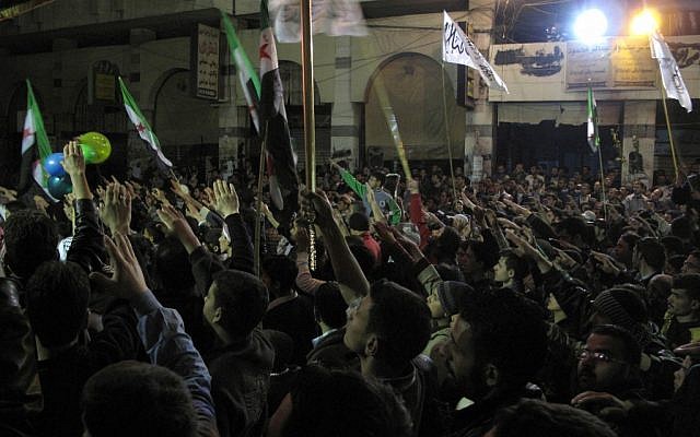 Syrians raise their hands vowing to continue fighting until President Bashar Assad's regime falls during a Damascus protest last week. (photo credit: AP)