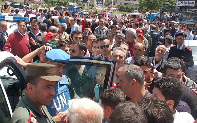 A UN observer and Syrian army officer listen to Syrian citizens during their visit to Homs on Monday (photo credit: AP/SANA)
