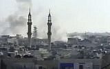 Smoke rising from buildings in Homs, Syria, in April 2012 (photo credit: AP/Shaam News Network via AP video)