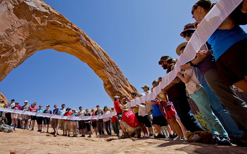 Participants in the Passover in the Desert of Moab program reading the Exodus story from the Torah under Corona Arch with the 'Adventure Rabbi,' Jamie Korngold. (photo credit: Jeff Finkelstein/JTA)