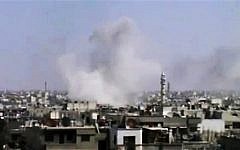 In this image made from amateur video released by the Syrian Media Council, smoke rises following purported shelling in Homs, Syria. (Photo credit: AP Photo/Syrian Media Council via AP video)