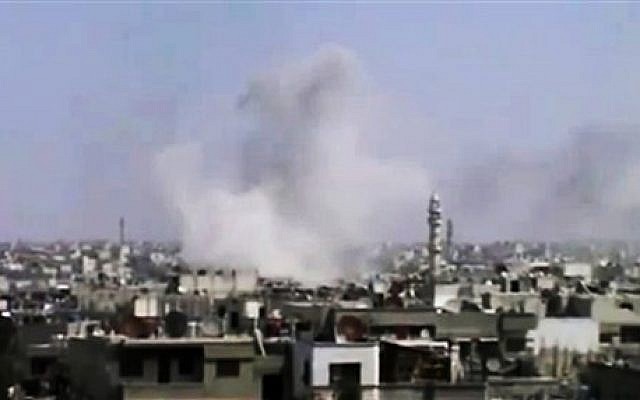 In this image made from amateur video released by the Syrian Media Council, smoke rises following purported shelling in Homs, Syria. (Photo credit: AP Photo/Syrian Media Council via AP video)