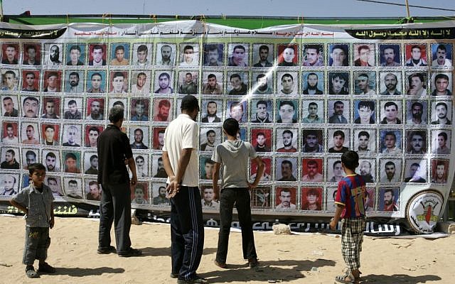 Gazans stand in front of a banner showing portraits of Palestinians held in Israeli jails in October 2011 in Rafah, in the southern Gaza Strip (photo credit: Abed Rahim Khatib/Flash 90) Gazans stand in front of a banner showing portraits of Palestinians held in Israeli jails in October 2011 in Rafah, in the southern Gaza Strip (photo credit: Abed Rahim Khatib/Flash 90)