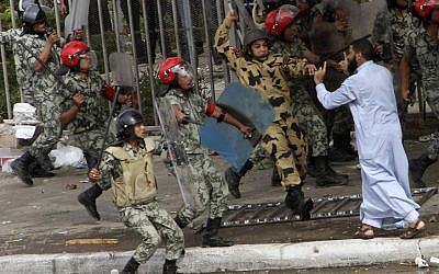 Egyptian soldiers raise their batons at a protester during clashes outside the Ministry of Defense in Cairo, Egypt, Friday. (photo credit: AP)