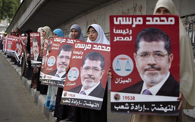 Egyptian women line up to form a human chain as they hold posters of Muslim Brotherhood presidential candidate, Mohammed Morsi, in Cairo, on Thursday (photo credit: AP/Fredrik Persson)