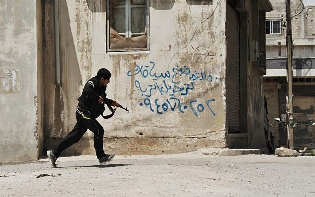 A Syrian rebel runs for cover in Homs (photo credit: AP/Fadi Zaidan/File)