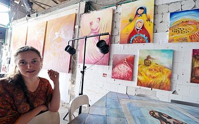 Dina Argov with some of her paintings on display at the Container in the background (photo credit: David Katz)