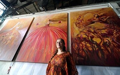 Dina Argov, at the Container restaurant/artspace in Jaffa, with her triptych 'Painting Women' behind her (photo credit: David Katz)