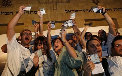 New immigrants to Israel from France hold up their new Israeli ID cards (illustrative; photo credit: Miriam Alster/Flash90)
