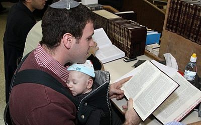 A father wearing his baby while learning (photo credit: Gershon Elinson/Flash 90)