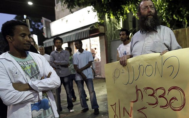 An African migrant stands next to a protester calling on the government to the solve the problem of illegal migration, at a Tel Aviv rally, in May (photo credit: Tsafrir Abayov/Flash90) An African migrant stands next to a protester calling on the government to the solve the problem of illegal migration, at a Tel Aviv rally, in May (photo credit: Tsafrir Abayov/Flash90)