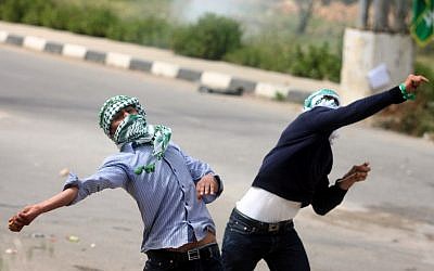 Palestinian protesters throw stones at Israeli troops outside the Ofer military prison near Ramallah on Wednesday. (photo credit: Issam Rimawi/Flash90)