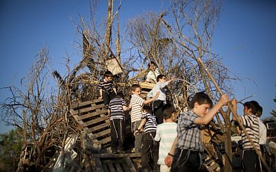 Children build a big bonfire for the Lag B'Omer festival, in Safed, northern Israel, April 30, 2018. (David Cohen/Flash90)
