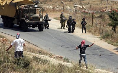 Palestinian protesters throw stones towards Israeli border police during a weekly demonstration in the village of Nabi Saleh near Ramallah. (photo credit: Issam Rimawi/Flash90)