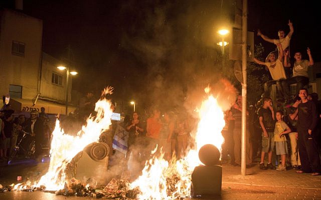 Anti-migrant protesters burn trash cans during a rally in Tel Aviv (photo credit: Tali Mayer/Flash90)