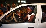 A migrant whose window was smashed during a demonstration in south Tel Aviv Wednesday. (photo credit: Roni Schutzer/Flash 90)
