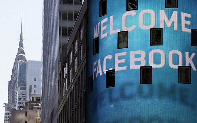 The Chrysler Building is visible behind the animated facade of the Nasdaq MarketSite, welcoming the Facebook IPO, in New York's Times Square, Friday. (photo credit: AP)