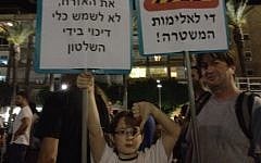 Itamar (left), and his father, Yossi Rosenbaum, carrying signs against police brutality at the social protest in Tel Aviv Saturday. "Next time, I'm going to make a cool new sign," said Itamar. (photo credit: Michal Shmulovich/Times of Israel)