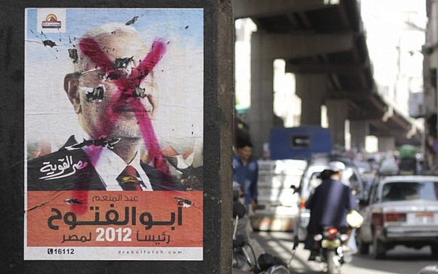 Egyptians pass by a defaced poster of a presidential candidate, Abdel-Moneim Abolfotoh in Cairo, Egypt, Monday, May, 21, 2012 (photo credit: AP/Hasan Jamali) Egyptians pass by a defaced poster of a presidential candidate, Abdel-Moneim Abolfotoh in Cairo, Egypt, Monday, May, 21, 2012 (photo credit: AP/Hasan Jamali)