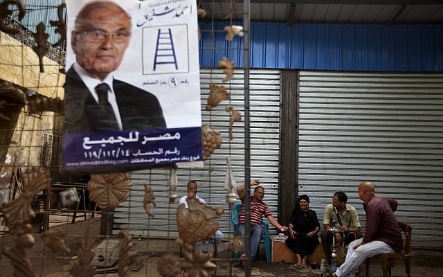 Egyptians sit at a coffee shop near a poster of Egyptian presidential candidate Ahmed Shafiq with Arabic that reads, "Ahmed Shafiq, Egypt is for all," in Cairo, Egypt, Tuesday, May 22, 2012 (AP/Fredrik Persson)