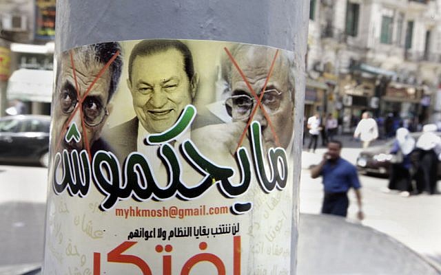 Egyptians walk near a poster showing ousted president Hosni Mubarak, center, and presidential candidates Amr Moussa, left, Mubarak's foreign minister for 10 years, and Ahmed Shafiq, a former Air Force commander and civil aviation minister whom Mubarak made prime minister during his last days in power, with Arabic that reads, "they will not rule," in Cairo, Egypt, Monday, May 21, 2012 (photo credit: AP/Amr Nabil) Egyptians walk near a poster showing ousted president Hosni Mubarak, center, and presidential candidates Amr Moussa, left, Mubarak's foreign minister for 10 years, and Ahmed Shafiq, a former Air Force commander and civil aviation minister whom Mubarak made prime minister during his last days in power, with Arabic that reads, "they will not rule," in Cairo, Egypt, Monday, May 21, 2012 (photo credit: AP/Amr Nabil)
