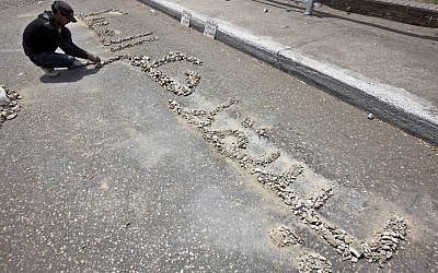An Egyptian protester arranges rocks to read in Arabic: "down with military rule," on the road leading to the Ministry of Defense in Cairo, Egypt, Tuesday (photo credit: AP/Fredrik Persson)