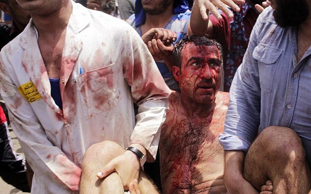 A medic helps a wounded man during clashes outside the Defense Ministry in Cairo on Wednesday. (photo credit: Mostafa El Shemy/AP) A medic helps a wounded man during clashes outside the Defense Ministry in Cairo on Wednesday. (photo credit: Mostafa El Shemy/AP)