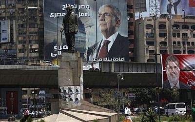 A statue of Nobel laureate Naguib Mahfouz with electoral advertisements for presidential candidates Amr Moussa, left, and Mohammed Morsi, right, in Cairo, Egypt. (photo credit: AP/Nasser Nasser)