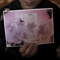 Bara, a daughter of Thaer Halahleh, holds a picture of her father, center, and her uncles inside the family house in the West Bank Village of Kharas near Hebron. Thaer is in administrative detention for the past 24 months and is on a hunger strike for well over 70 days. (photo credit: AP/Bernat Armangue)