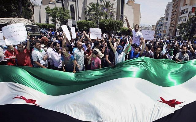 Anti-Assad regime protesters wave a giant Syrian revolutionary flag during a demonstration in Beirut in May (photo credit: AP/Bilal Hussein)