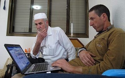 Mohammed Faour, right, and his father, Amin, who live in the village of Shaab in northern Israel, looking for relatives on Facebook. (photo credit: AP/Ben Hubbard)