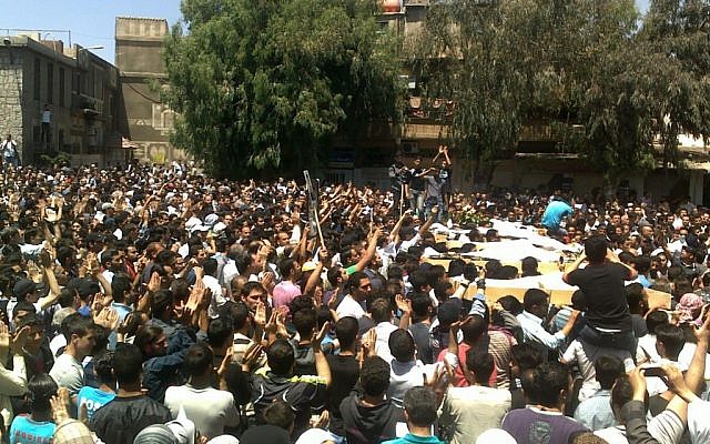 Anti-Syrian regime mourners shout slogans against President Bashar Assad as they carry the bodies of five protesters who were killed by Syrian security forces on Friday (photo credit: AP)