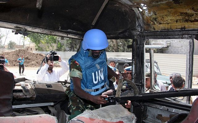 A UN observer photographs a military bus damaged by a roadside bomb near Damascus on Wednesday (photo credit: AP/Bassem Tellawi) A UN observer photographs a military bus damaged by a roadside bomb near Damascus on Wednesday (photo credit: AP/Bassem Tellawi)