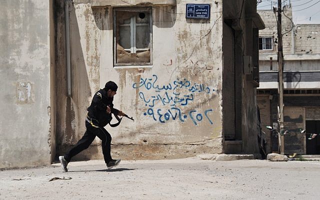 A Syrian opposition fighter runs for cover in Homs last month (photo credit: Fadi Zaidan/AP)
