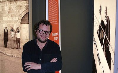 Curator Dmitrij Belkin next to a photo of Axel and Friede Springer looking down from an El-Al-airplane. (Igal Avidan)