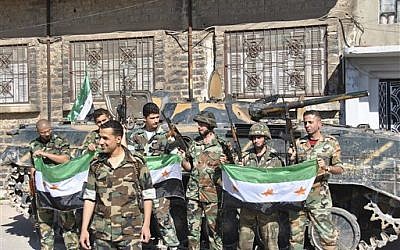 Syrian army soldiers hold the Syrian revolution flags shortly after they defected and joined the rebels, in Homs province on Saturday (AP/Fadi Zaidan)