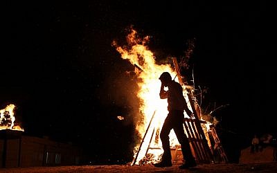 A child adds wood to a Lag Ba'omer bonfire in Betar Illit on Wednesday night. (photo credit: Nati Shohat/Flash90)