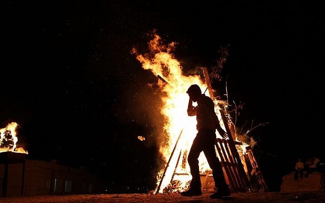 A child adds wood to a Lag Ba'omer bonfire in Betar Illit on Wednesday night. (photo credit: Nati Shohat/Flash90)
